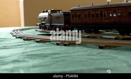 Closeup vintage Modell elektrische Zug von einer Dampflokomotive und einer grünen Pkw, die auf den Schienen gebildet Stockfoto