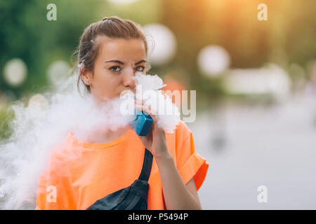 Hübsche junge Mädchen vape Beliebte ecig Gadget, vaping Gerät. Happy brunette vaper Mädchen mit E-Cig. Portrait von Raucher weibliche Modell mit elektronischen Cigarett Stockfoto