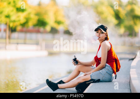 Hübsche junge Asiatin vape Beliebte ecig Gadget, vaping Gerät. Happy brunette vaper Mädchen mit E-Cig. Portrait von Raucher weibliche Modell mit elektronischen ci Stockfoto