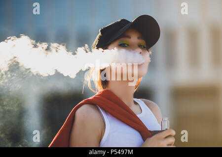 Hübsche junge Asiatin vape Beliebte ecig Gadget, vaping Gerät. Happy brunette vaper Mädchen mit E-Cig. Portrait von Raucher weibliche Modell mit elektronischen ci Stockfoto