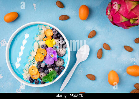 Smoothie Schale mit Früchten, Beeren, Nüsse und Blumen. Tropische gesunden Smoothie Dessert. Gesundes Frühstück, Vegetarisch, Diät Konzept. Ansicht von oben, Fla Stockfoto
