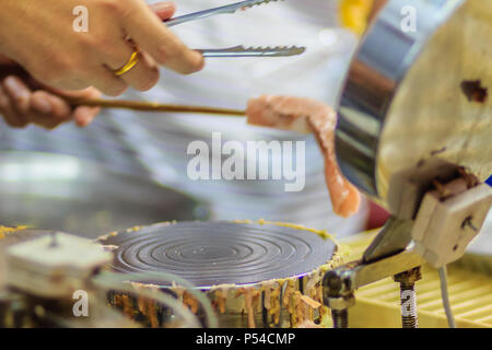 Nahaufnahme der Hand der Anbieter während des Kochens für knusprige Brötchen oder tootsie Thai Snack, thailändisches Dessert Essen im Thai Stil namens 'Thong muan' oder 'Tong Muan", eine Art Stockfoto