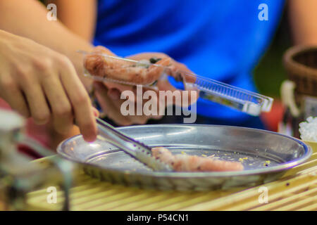 Nahaufnahme der Hand der Anbieter während des Kochens für knusprige Brötchen oder tootsie Thai Snack, thailändisches Dessert Essen im Thai Stil namens 'Thong muan' oder 'Tong Muan", eine Art Stockfoto