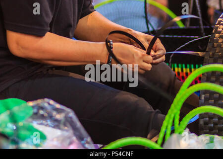 Nahaufnahme der Hand des Weber während des Weben Korb aus Kunststoff hergestellt. Weaver ist weben Kunststoff Warenkorb zeigen bei der Tourist in Bangkok, Thailand. Stockfoto