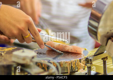 Nahaufnahme der Hand der Anbieter während des Kochens für knusprige Brötchen oder tootsie Thai Snack, thailändisches Dessert Essen im Thai Stil namens 'Thong muan' oder 'Tong Muan", eine Art Stockfoto