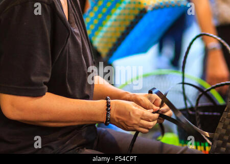 Nahaufnahme der Hand des Weber während des Weben Korb aus Kunststoff hergestellt. Weaver ist weben Kunststoff Warenkorb zeigen bei der Tourist in Bangkok, Thailand. Stockfoto