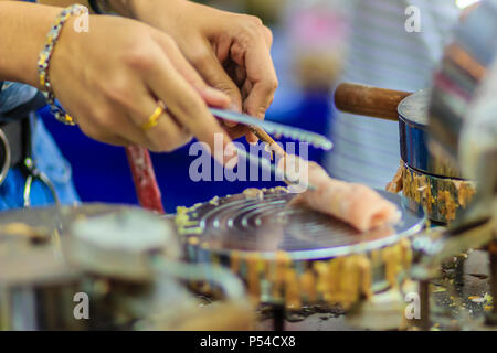 Nahaufnahme der Hand der Anbieter während des Kochens für knusprige Brötchen oder tootsie Thai Snack, thailändisches Dessert Essen im Thai Stil namens 'Thong muan' oder 'Tong Muan", eine Art Stockfoto