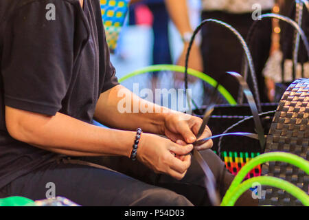 Nahaufnahme der Hand des Weber während des Weben Korb aus Kunststoff hergestellt. Weaver ist weben Kunststoff Warenkorb zeigen bei der Tourist in Bangkok, Thailand. Stockfoto