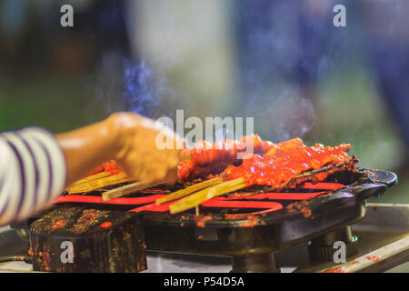 Close up Anbieter während des Grillens Südlichen spicy Chicken. 'Kor Lae" gegrilltes Huhn ist beliebt in Nakhon Sri Thammarat, im Süden von Thailand, wenig Stockfoto