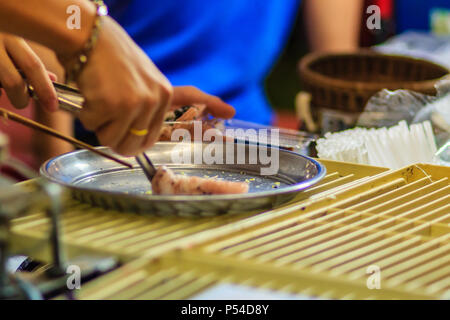 Nahaufnahme der Hand der Anbieter während des Kochens für knusprige Brötchen oder tootsie Thai Snack, thailändisches Dessert Essen im Thai Stil namens 'Thong muan' oder 'Tong Muan", eine Art Stockfoto