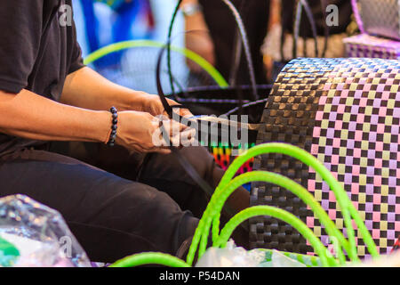 Nahaufnahme der Hand des Weber während des Weben Korb aus Kunststoff hergestellt. Weaver ist weben Kunststoff Warenkorb zeigen bei der Tourist in Bangkok, Thailand. Stockfoto