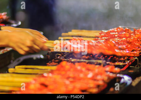 Close up Anbieter während des Grillens Südlichen spicy Chicken. 'Kor Lae" gegrilltes Huhn ist beliebt in Nakhon Sri Thammarat, im Süden von Thailand, wenig Stockfoto