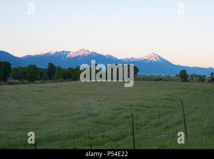 Die schneebedeckten Berge in der Absaroka Range in Montana mit einem eingezäunten Weide im Vordergrund. Bei Sonnenaufgang fotografiert. Stockfoto