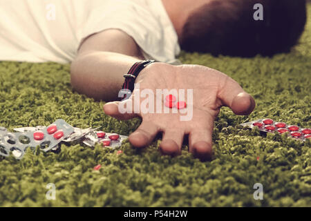 Der Mann Selbstmord durch Überdosierung von Medikamenten. Nahaufnahme einer Überdosis Pillen und Süchtigen. red Tabletten in die Hand eines jungen Mannes Stockfoto