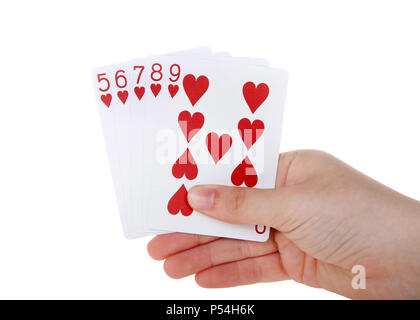 Junge weibliche Hand, die Spielkarten, ein Straight Flush. Ein Straight Flush ist eine Sequenz von fünf Karten derselben Farbe. Herzen. Stockfoto