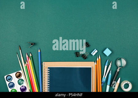 Der Schüler Schreibtisch mit stationären auf grünem Hintergrund. Vorbereitung auf die Schule. Stockfoto