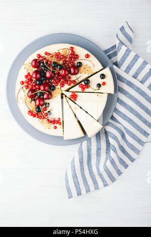 New York Käsekuchen mit Beeren auf weiße Holztisch. Ansicht von oben. Rote Johannisbeere, schwarze Johannisbeere und Kirsche. Stockfoto
