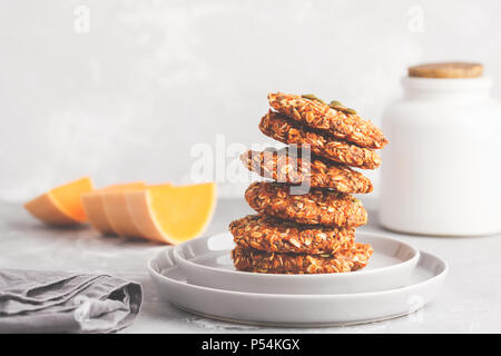 Stapel von natürlichen Haferflocken pumpkin Cookies auf eine graue Platte, halloween Essen, veganes Essen Konzept. Stockfoto