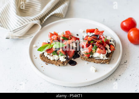 Toast mit Feta Käse, Tomaten und Balsamico Sauce auf eine weiße Platte, selektiver Fokus Stockfoto