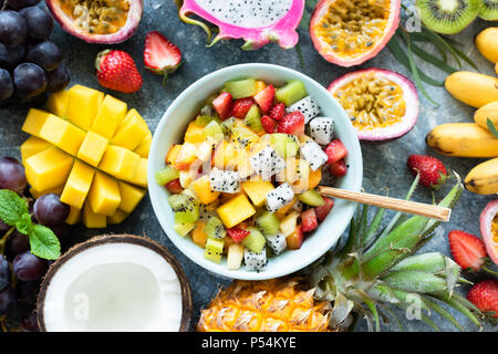 Tropischer Obstsalat mit Mango und pitaya in der Schüssel. Gesunde Salate. Mango, Kokosnuss, Ananas, pitaya, Mango und Passionsfrucht Obstsalat Stockfoto