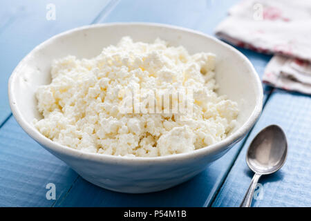 Ricotta oder Hüttenkäse in weißen Schale auf der blauen Tabelle. Gesunde Milchprodukte. Oder tvorog Farmer's Käse. Stockfoto