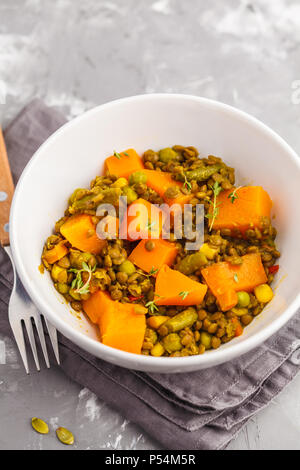 Linsensuppe mit Kürbis Ragout in einer weißen Schüssel auf einem grauen Hintergrund. Gesunde vegane Ernährung Konzept. Stockfoto