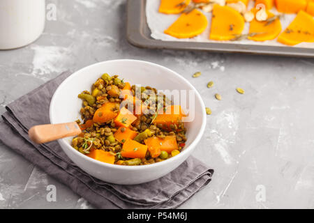 Linsensuppe mit Kürbis Ragout in einer weißen Schüssel auf einem grauen Hintergrund. Gesunde vegane Ernährung Konzept. Stockfoto