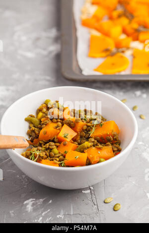 Linsensuppe mit Kürbis Ragout in einer weißen Schüssel auf einem grauen Hintergrund. Gesunde vegane Ernährung Konzept. Stockfoto