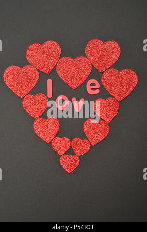 Ein Herz aus Herzen verschiedener Größe auf einem schwarzen Hintergrund mit dem Wort "Liebe" Stockfoto