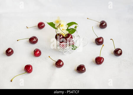 Miniatur Warenkorb bike, Trolley mit frischen Kirsche auf hellen Hintergrund wih verstreut reif Berrys. Konzept der gesunden Ernährung, Entgiftung, Vitamine, Diät Stockfoto