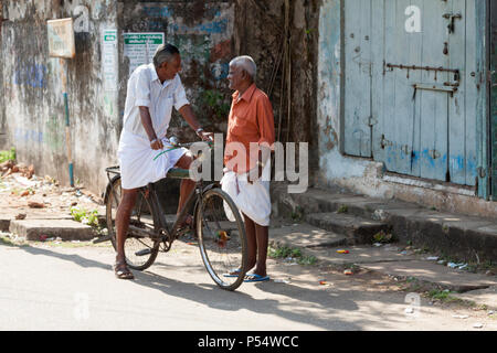 Mann auf einem Fahrrad ein Gespräch mit einem Mann auf der Straße in der alten kolonialen Bereich von Kochi, Kerala, Indien. Stockfoto