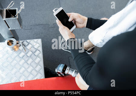 Nicht erkennbare Adaptive Athlet mit Smartphone in der Turnhalle Stockfoto