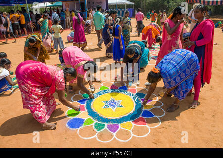 AUROVILLE, INDIEN - 4. März 2018: Sangamam Festival. Frauen zeichnen einen kolam Stockfoto