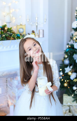 Kleine hübsche Mädchen Kerze halten und in der Nähe von Weihnachten Baum. Stockfoto