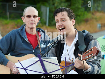 Seatac, Washington, USA. 24 Juni, 2018. Joel Rodriguez führt außerhalb der Bundesrepublik Detention Center in Seatac, Washington singen, Anfang Juni 24 während einer Gebetsvigil in Unterstützung der Zugewanderten Eltern im Gefängnis, die von ihren Kindern getrennt wurden. Hinter ihm ist David Reinholz. Die mahnwache wurde durch die Vereinigte Methodistische Kirche gefördert. Credit: Paul Jeffrey/Alamy leben Nachrichten Stockfoto