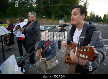 Seatac, Washington, USA. 24 Juni, 2018. Joel Rodriguez führt außerhalb der Bundesrepublik Detention Center in Seatac, Washington singen, Anfang Juni 24 während einer Gebetsvigil in Unterstützung der Zugewanderten Eltern im Gefängnis, die von ihren Kindern getrennt wurden. Hinter ihm ist David Reinholz. Die mahnwache wurde durch die Vereinigte Methodistische Kirche gefördert. Credit: Paul Jeffrey/Alamy leben Nachrichten Stockfoto