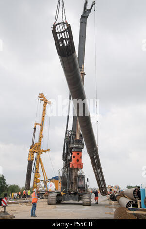 19 Juni 2018, Deutschland, Chile: ein Joint Venture, das von zwei großen Bauunternehmen arbeiten auf der Grundlage einer behelfsmäßigen Brücke an der Baustelle der A20 Autobahn (Luftaufnahme mit einer Drohne). Die Gesamtkosten für den Bau der provisorischen Brücke belaufen sich auf insgesamt 51,3 Mio. Euro nach Verkehrsminister Hochwasserstände, von denen 31 Mio. sind vorgesehen für die Stiftung arbeitet. Insgesamt 232 Strommasten - mit einem Durchmesser von 1,2 Metern und einer durchschnittlichen Länge von 24 Meter - sind für den Bau erforderlich. Ein in der Nähe der 100 Meter langen Strecke der A 20 sank in der sumpfigen gr Stockfoto