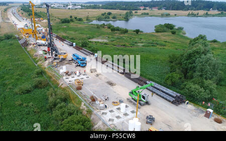 19 Juni 2018, Deutschland, Chile: ein Joint Venture, das von zwei großen Bauunternehmen arbeiten auf der Grundlage einer behelfsmäßigen Brücke an der Baustelle der A20 Autobahn (Luftaufnahme mit einer Drohne). Die Gesamtkosten für den Bau der provisorischen Brücke belaufen sich auf insgesamt 51,3 Mio. Euro nach Verkehrsminister Hochwasserstände, von denen 31 Mio. sind vorgesehen für die Stiftung arbeitet. Insgesamt 232 Strommasten - mit einem Durchmesser von 1,2 Metern und einer durchschnittlichen Länge von 24 Meter - sind für den Bau erforderlich. Ein in der Nähe der 100 Meter langen Strecke der A 20 sank in der sumpfigen gr Stockfoto