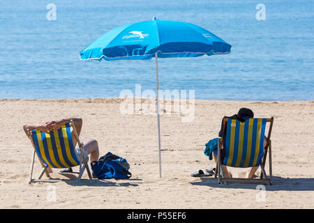 Bournemouth, Dorset, Großbritannien. Juni 2018. UK Wetter: Sonnenanbeter fahren an einem weiteren schönen heißen sonnigen Tag mit ungebrochenem blauem Himmel und Sonnenschein an die Küste, wenn die Temperaturen weiter steigen. Strandgänger sitzen in Liegestühlen und genießen die Sonne unter dem Sonnenschirm am Bournemouth Strand. Quelle: Carolyn Jenkins/Alamy Live News Stockfoto