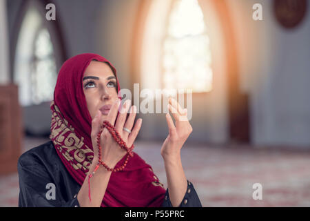 Junge muslimische Frau zu beten mit dem Rosenkranz in der Moschee Stockfoto