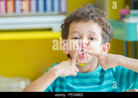 Portrait von Caucasious boy ein lustiges Gesicht in Klassenzimmer spielen im Kindergarten Vorschule, kid Bildung Stockfoto