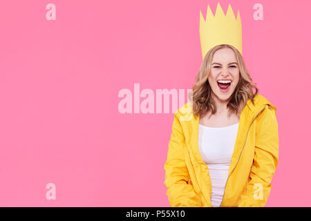 Schöne Mädchen im Teenageralter in hellem Gelb Jacke und Partei hat schreien vor begeisterung. Attraktive cool junge Frau mode Portrait über Pastell rosa. Stockfoto