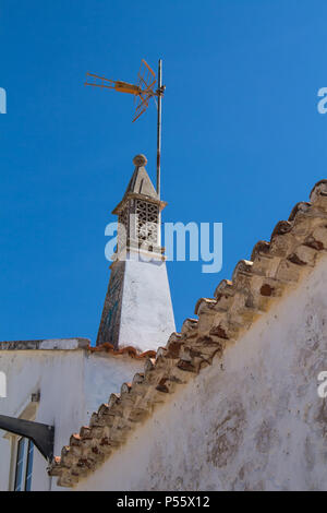 Detail eines Hauses mit einem traditionellen Kamin. Diagonale Linie von einem Dach. Strahlend blauen Himmel. Armacao de Pera, Algarve, Portugal Stockfoto