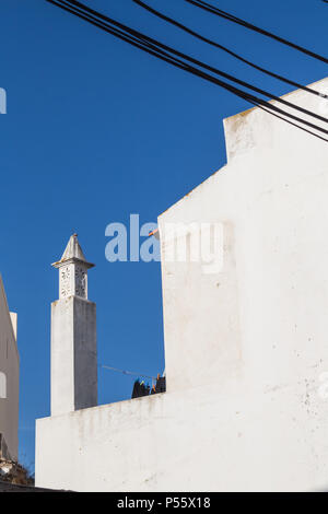 Weiße Fassade eines Gebäudes und einem traditionellen Kamin. Diagonale Linien der Kabel. Strahlend blauen Himmel. Armacao de Pera, Algarve, Portugal. Stockfoto