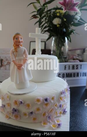 2 tier Katholische Erstkommunion Kuchen mit Puderzucker Figur eines Mädchens, weißes Kreuz und Lila und Zitrone Blumen und Licht, sagen Erste communiom Stockfoto