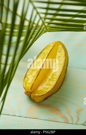 Star Fruit karambolen oder star Apple auf grünem Hintergrund mit Palmblättern, flach Stockfoto