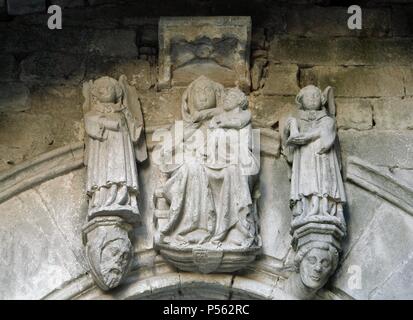 Spanien. Katalonien. Kirche Santa Maria Conesa. Jungfrau Maria. Im 14. Jahrhundert errichtet (1339-1347). Im gotischen Stil. Generalunternehmer Guillem Pedrola. Über der Tür des Tempels sind einige schöne Skulpturen aus Stein. Die Mitte ist der Jungfrau Maria (Santa Maria Conesa), sitzend mit ihr   Sohn in ihre Arme, ist in der gleichen Tonart geschnitzten Stein der Gewölbe. Portrait Köpfe sind wahrscheinlich der Generalunternehmer Guillem Pedrola und Steinmetz. Detail. Stockfoto