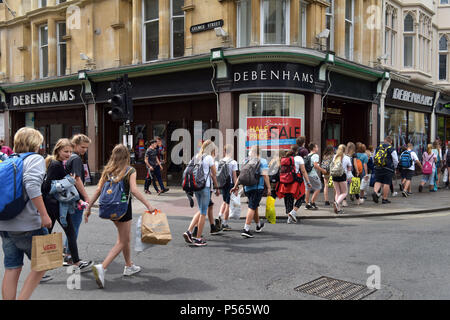 Kunden, Touristen und eine Linie von Studenten zu Fuß vorbei am Kaufhaus Debenhams an der Ecke der High Street, George Street in Oxford. Stockfoto