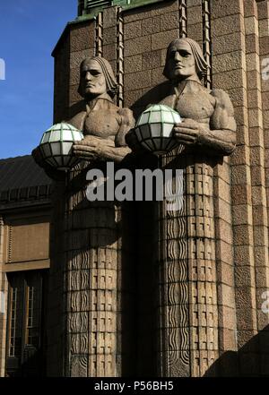 Finnland. Helsinki. Die torchbearer Lampen. Zwei der vier monumentalen Skulpturen aus Granit im Finnischen romantischen Stil, der 1904 vom Architekten Gottlieb Eliel Saarinen (1873-1950) und zwischen 1910-14 errichtet, von Bildhauer Emil Wikstrom (1864-1942). Sie schmücken die südlichen Eingang zum Hauptbahnhof und halten Sie Luftballons leuchten bei Nacht, der das Licht der Welt dar. Stockfoto