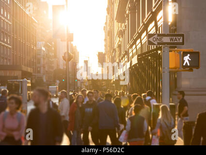 Diverse Masse von anonymen Personen auf einer belebten Straße in Manhattan, New York City mit hellem Sonnenlicht im Hintergrund glänzend Stockfoto